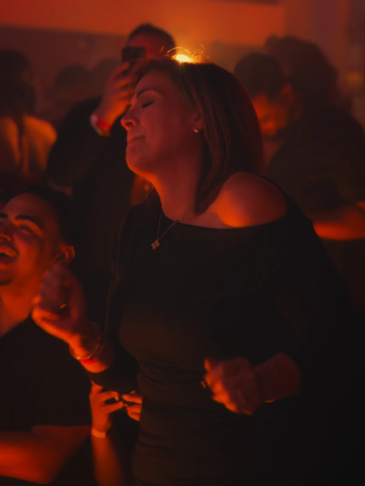 Gente bailando en la pista bajo luz cálida.