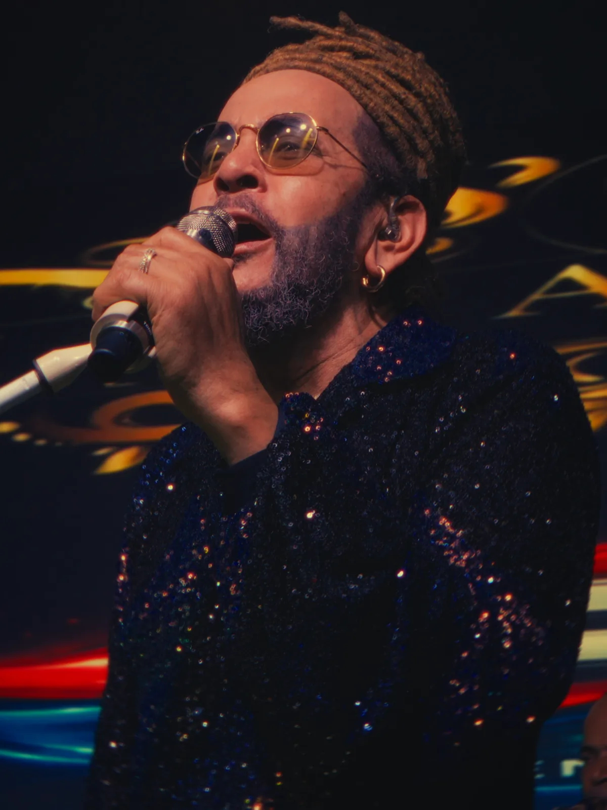 Toño Rosario cantando, con el logo dorado del salón detrás.